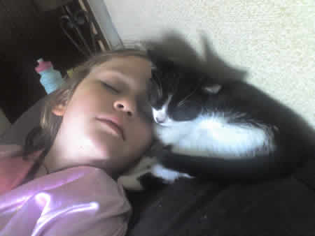 A black and white kitten and her friend asleep at the end of a long day